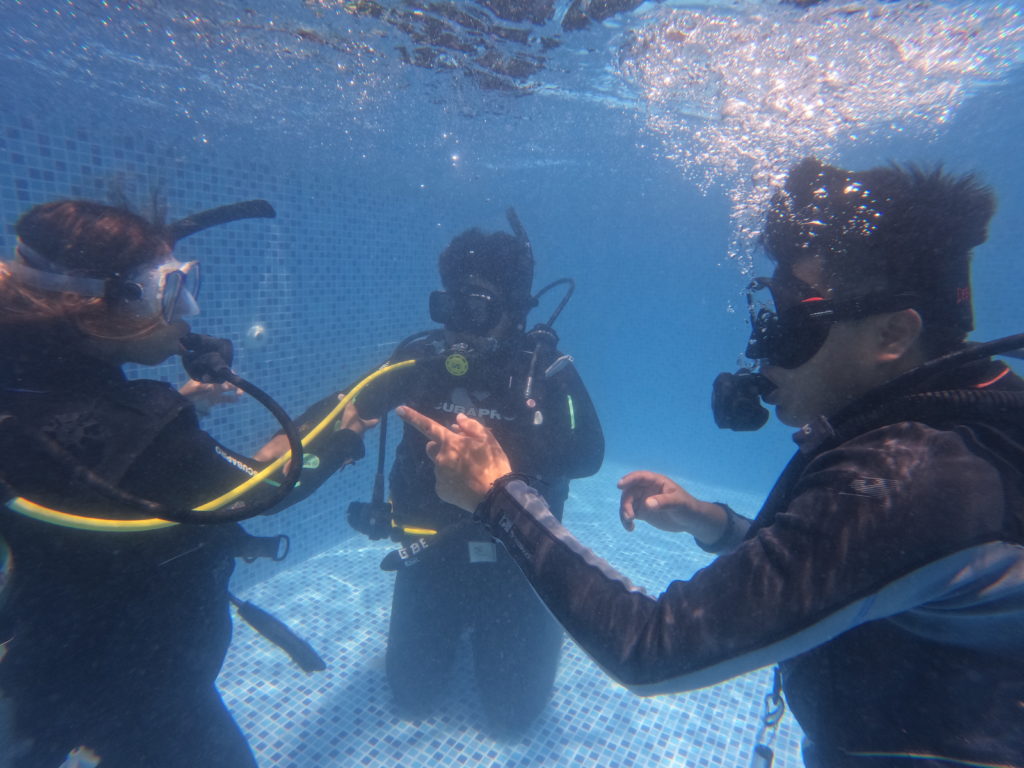 Students during a first pool session for a PADI Open Water Course under the watch full eye of their instructor.